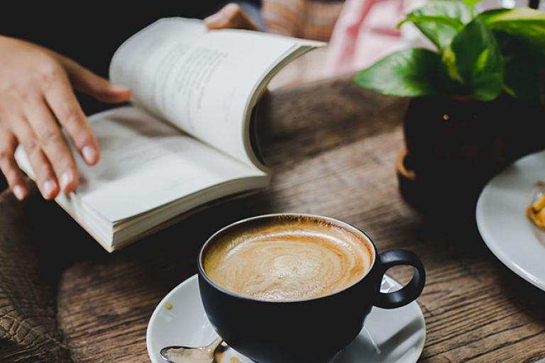 a person reading a book while enjoying a cup of coffee