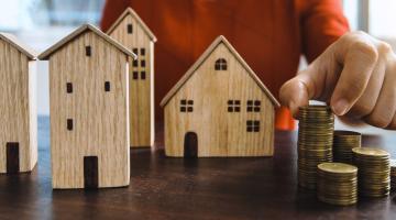 toy wooden houses next to a small pile of coins